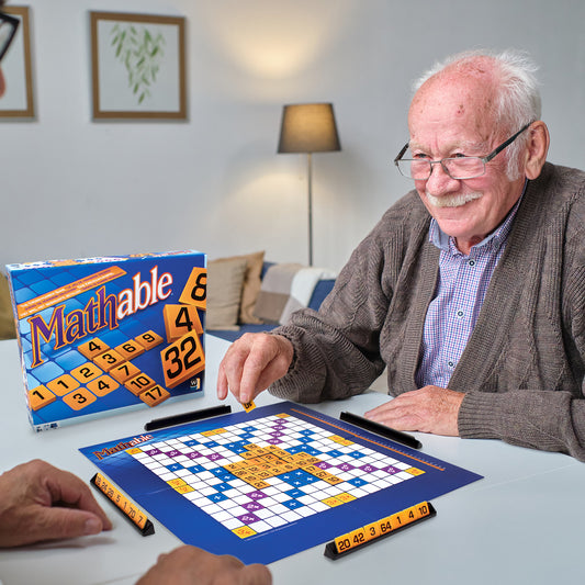 Elderly man enjoying playing Mathable board game focused on learning with math games during family game night