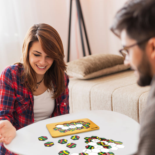 Two people enjoying a Tantrix strategy game with colorful hexagonal tiles on a white table indoors