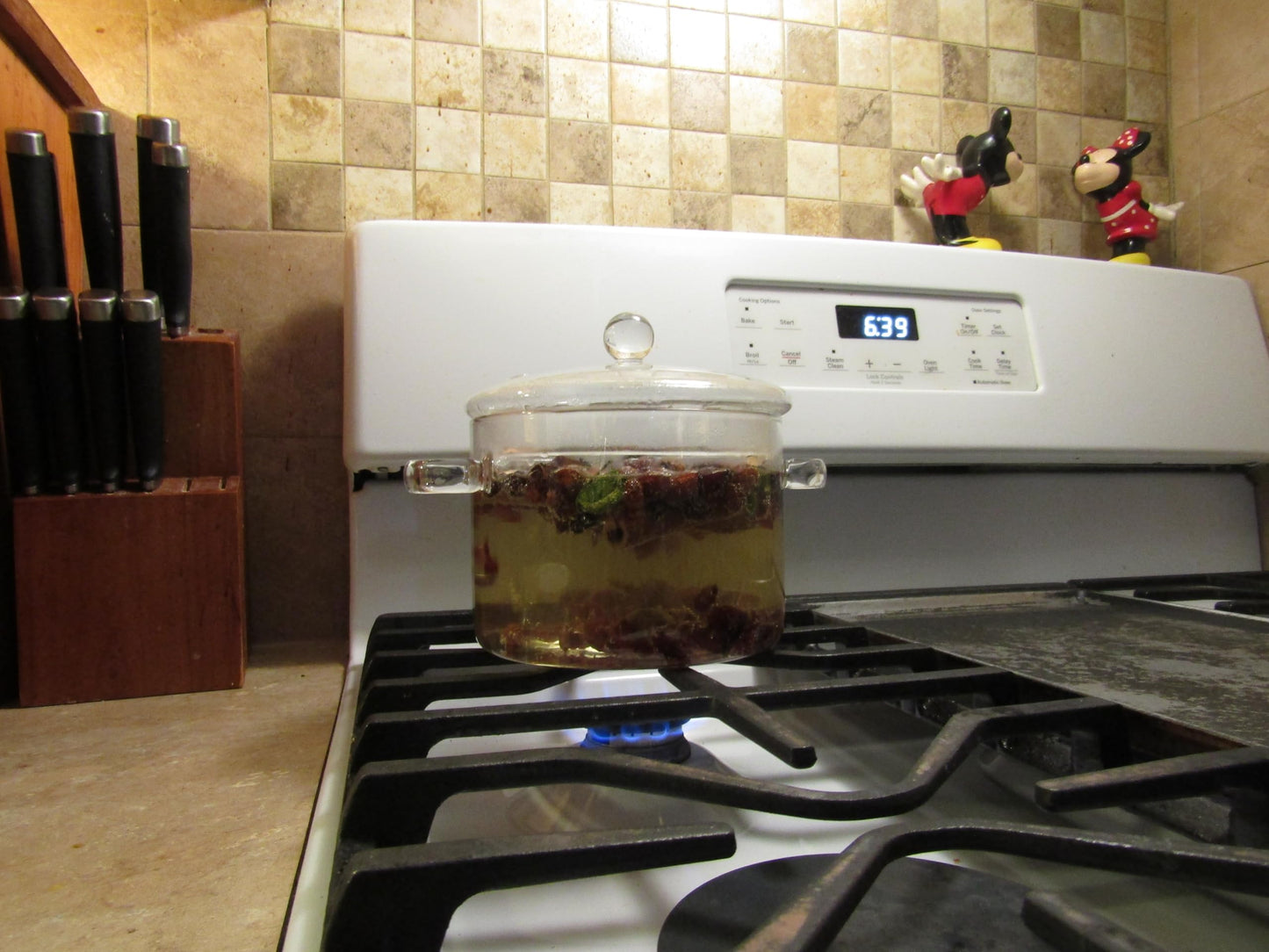 Cinnamon simmering potpourri heating in a clear glass pot on a gas stove with kitchen decor