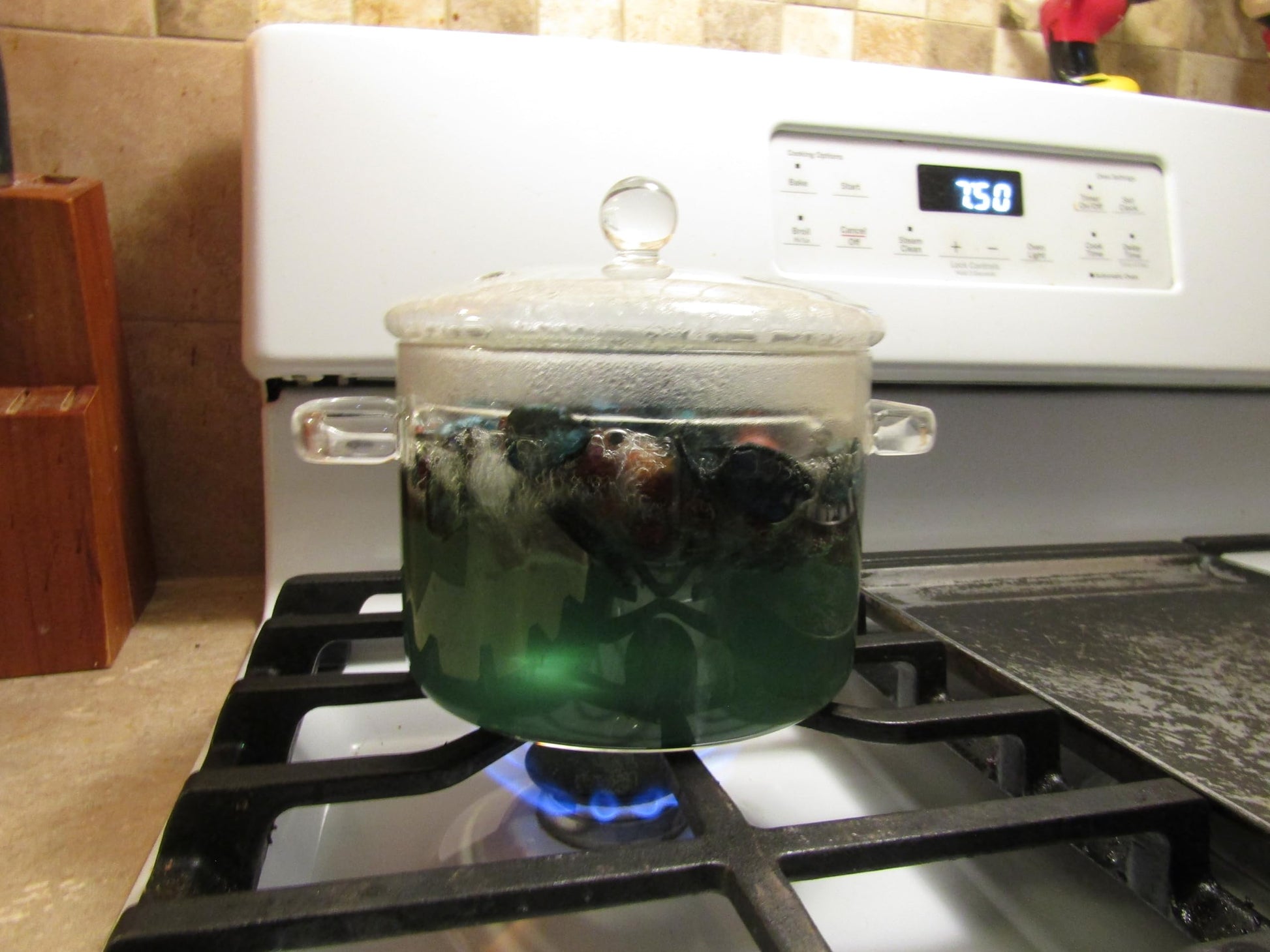 Herbal simmering potpourri in a glass pot on a stove with blue flame heating the mixture