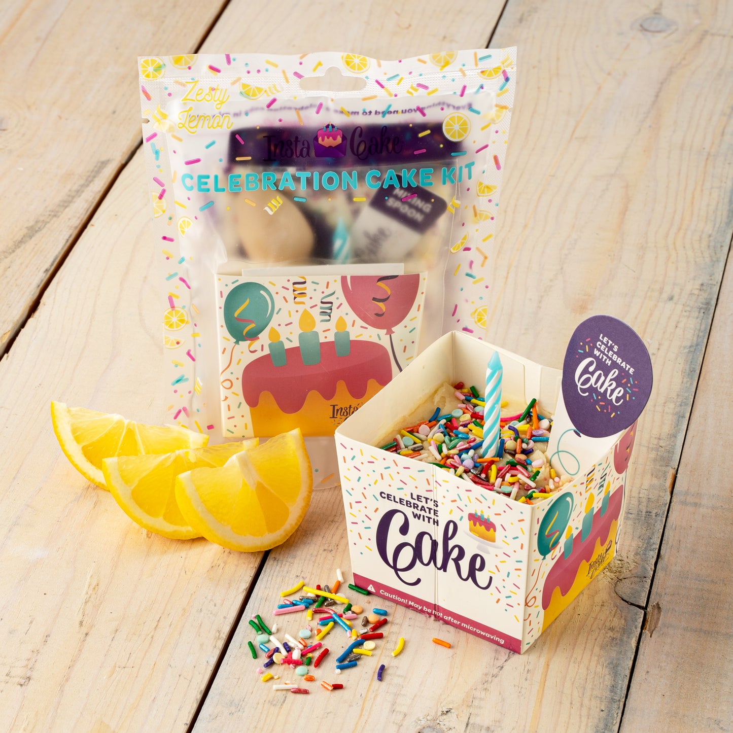 Instacake Cards lemon celebration cake kit with open sprinkle cup box and lemon wedges on wooden table