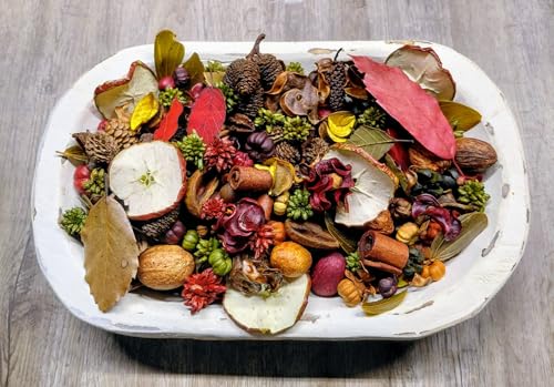 White wooden bowl of rustic autumn potpourri handmade with dried apple slices nuts cinnamon pods pine cones and leaves