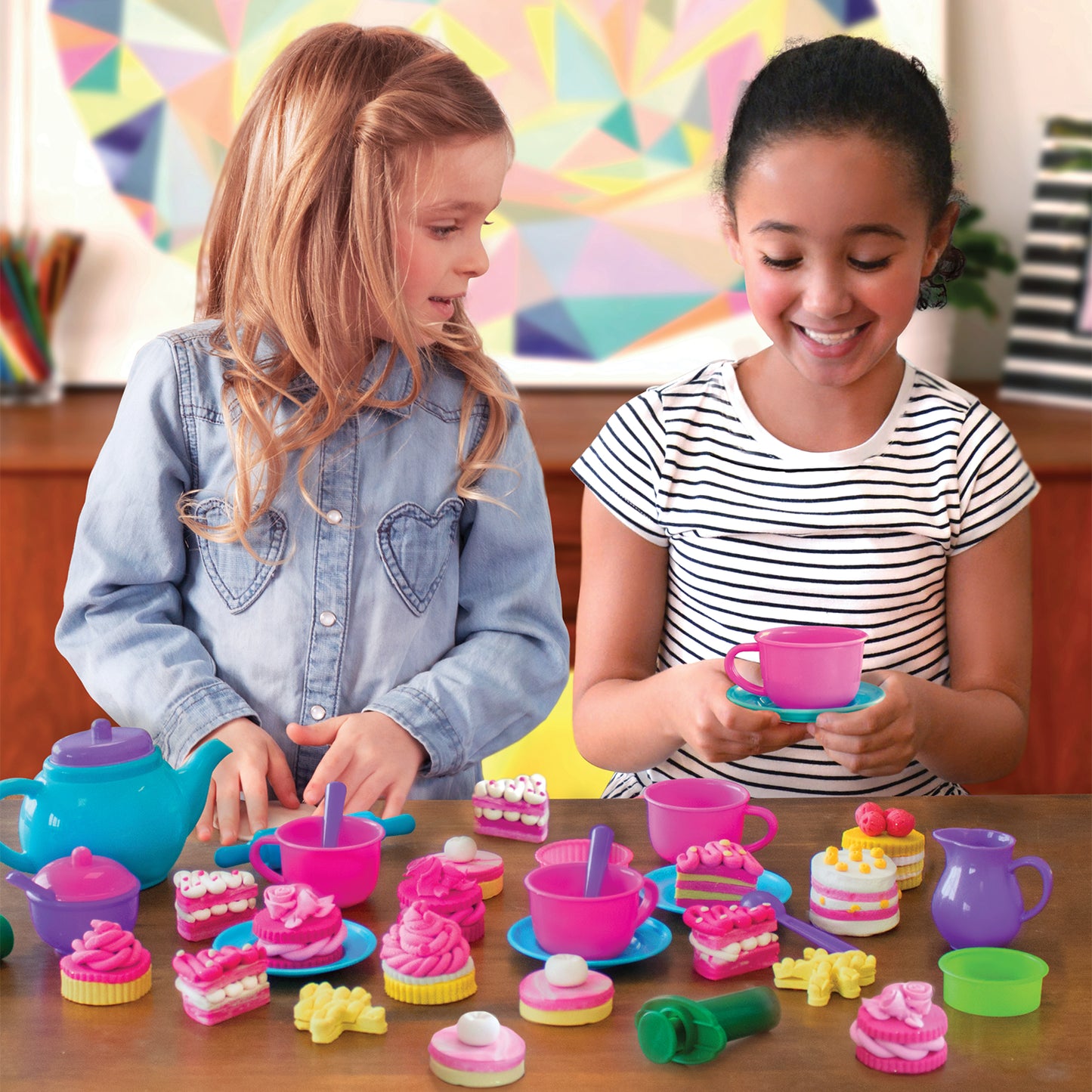 Two girls having a pretend tea party with pink and purple cups pastries and Tutti Frutti Sparkling Tea Time set