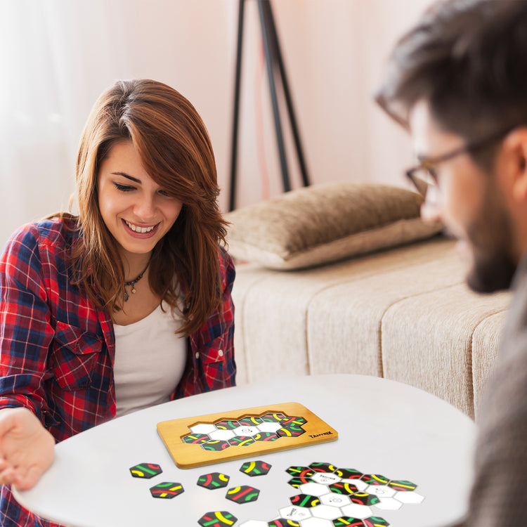 Two people enjoying a Tantrix strategy game with colorful hexagonal tiles on a white table indoors