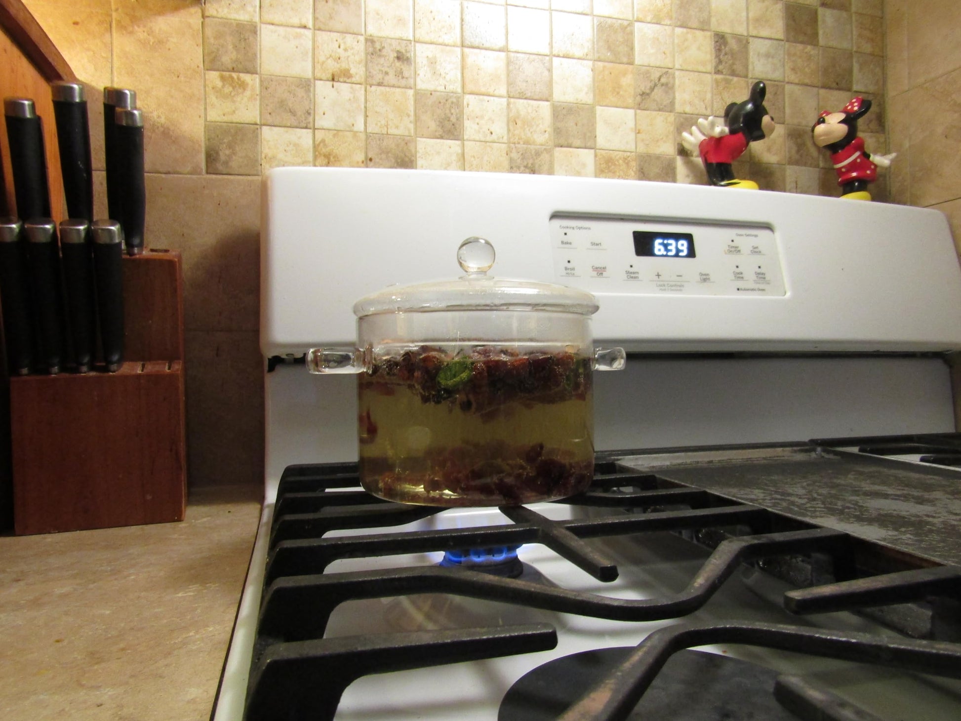 Cinnamon simmering potpourri heating in a clear glass pot on a gas stove with kitchen decor