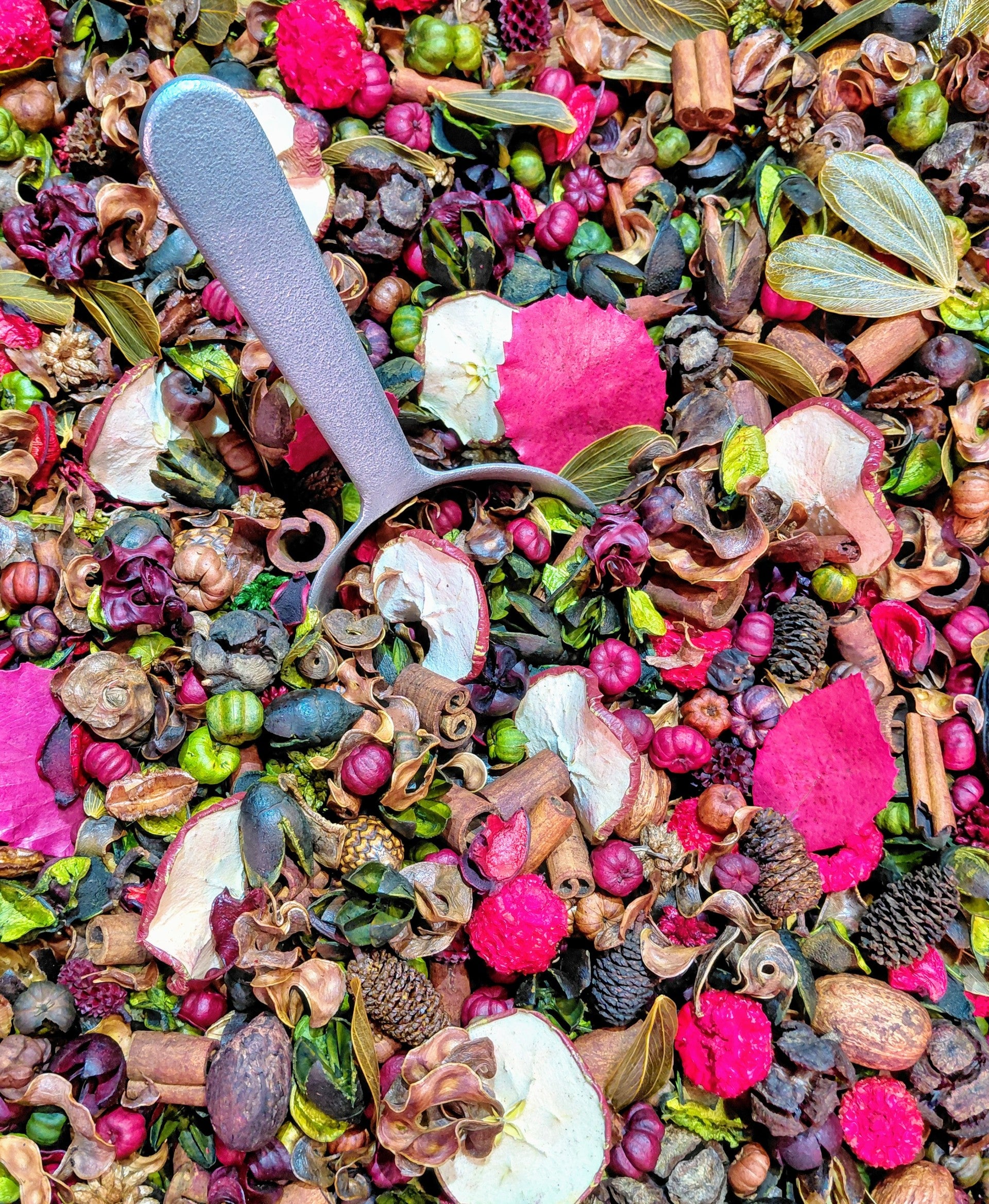 Colorful apple cinnamon potpourri mix with dried fruit, cinnamon sticks, and a silver scoop for home fragrance