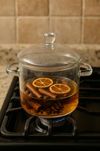 Cinnamon orange clove simmer oil in glass pot on stove with visible spices and citrus slices