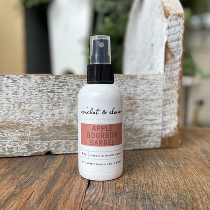 Cricket and Clover 4 oz linen and room spray bottle on wood labeled Apple Bourbon Barrel apple bourbon air freshener