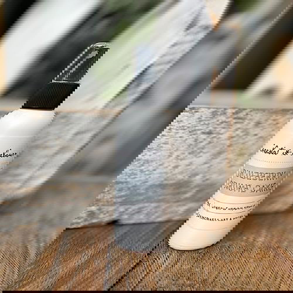 Cricket and Clover Blueberry Crumb Cake Potpourri Room Spray white bottle with black spray top on rustic wooden surface