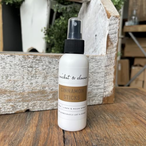 Cricket & Clover cinnamon stick room spray in white bottle with black spray cap on wooden surface