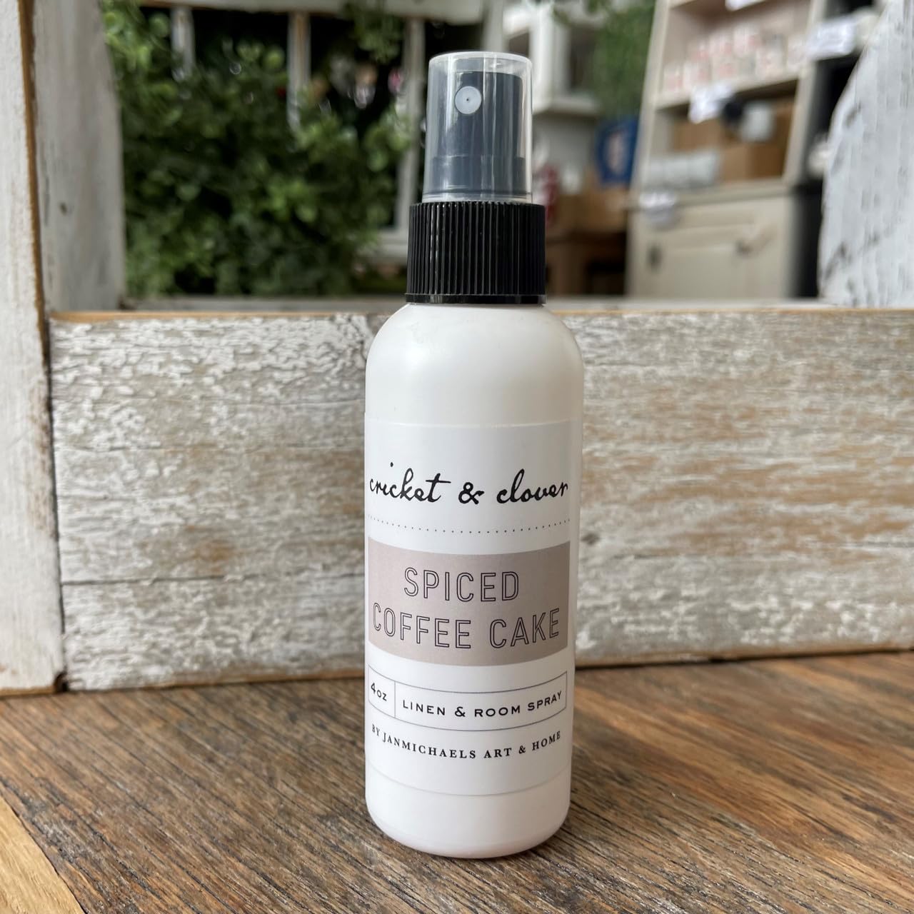 Cricket & Clover spiced coffee cake room spray in white bottle with black spray top on wooden surface