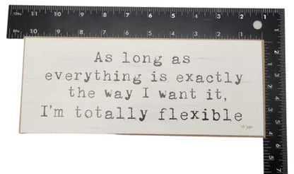 Funny wooden block sign with quote about flexibility in black text on white background
