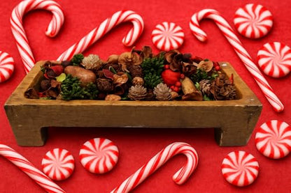 Peppermint potpourri bowl filler in a wooden dish surrounded by decorative candy canes