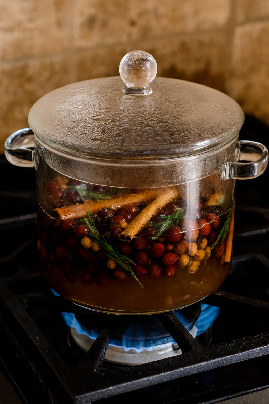 Cozy pine simmer potpourri in a glass pot with spices and berries on a stovetop