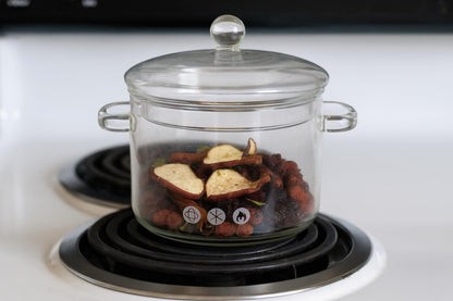 Glass pot on electric stove containing dried apple slices and spices for apple pie simmer potpourri