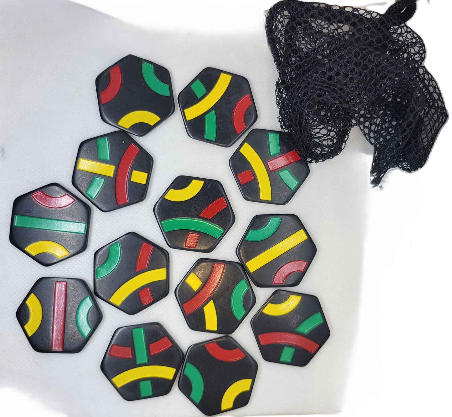 Tantrix replacement tiles pack with colorful curved lines on black hexagonal tiles beside a black mesh pouch