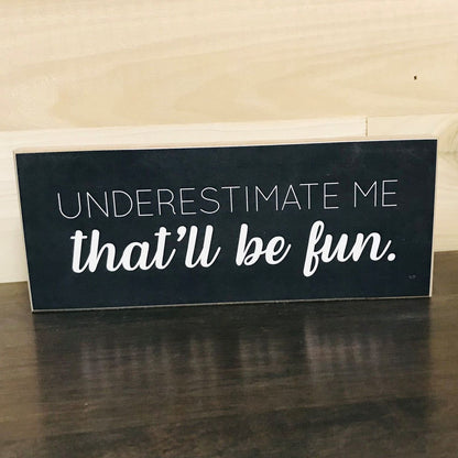 Jan Michaels Art & Home black wooden sign with white text reading underestimate me that will be fun sign